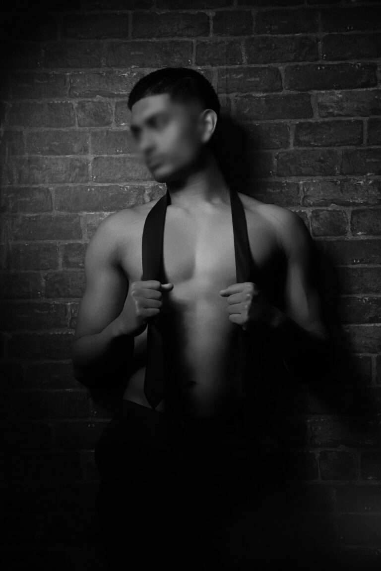 Man in black tie against brick wall. Blurred face